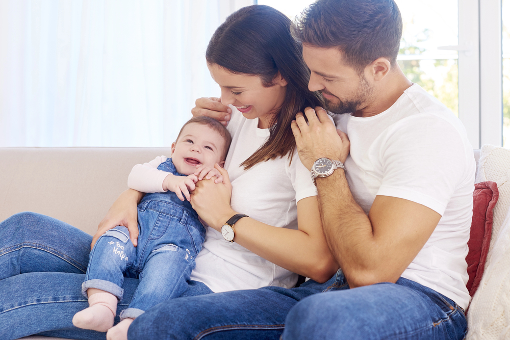 Shot of happy young family sitting on sofa with their baby girl.