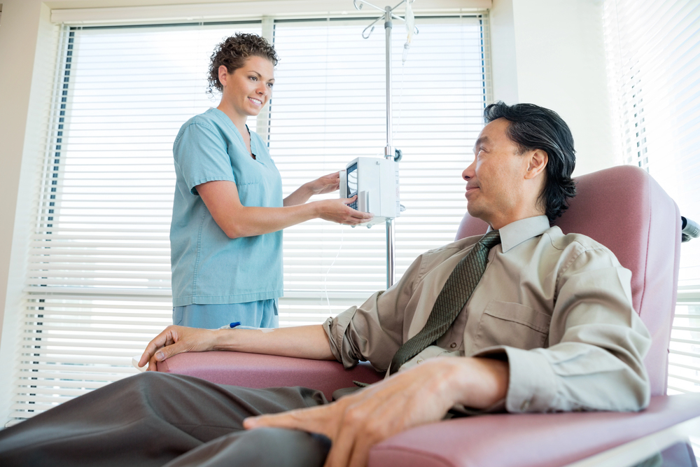 Nurse Looking At Patient While Adjusting IV Machine